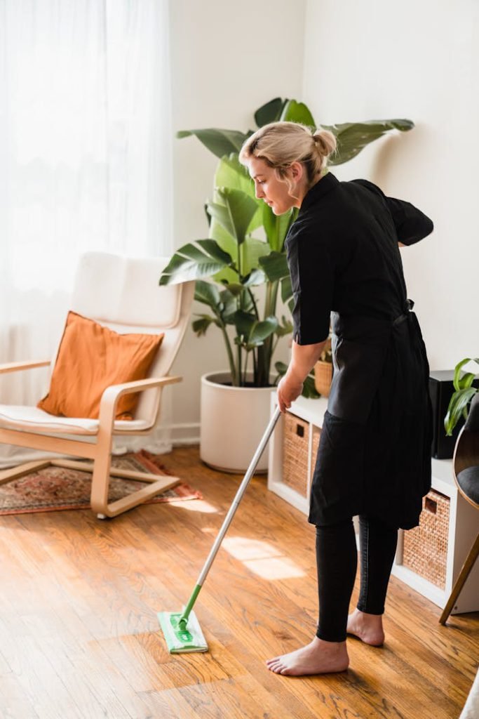 pexels-photo-9462143 A woman mops the floor in a sunlit room with modern decor and indoor plants.
